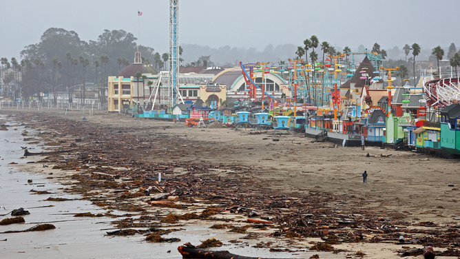 A lone person walks near driftwood storm debris washed up in front of the Santa Cruz Beach Boardwalk amusement park on January 11, 2023 in Santa Cruz, California. The San Francisco Bay Area and much of Northern California continues to get drenched by powerful atmospheric river events that have brought high winds and flooding rains. The storms have toppled trees, flooded roads and cut power to tens of thousands. Storms are lined up over the Pacific Ocean and are expected to bring more rain and wind through the end of the week.