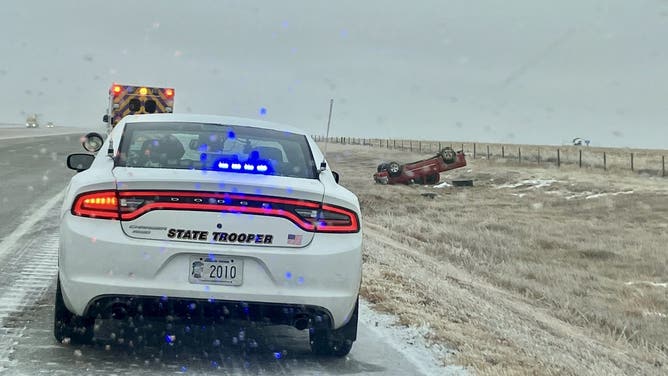 In the background, a red pickup truck rests upside side after flipping off of the road on January 18, 2023.