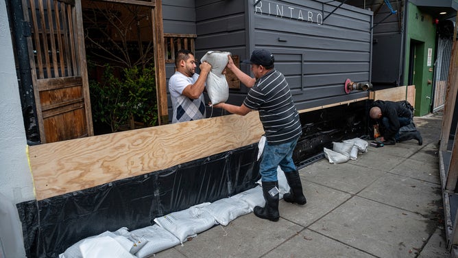 Workers build a flood protection barrier at the entrance to a business in the Mission District of San Francisco, California, US, on Tuesday, Jan. 3, 2023. While California tries to clean up from floods and mudslides that killed at least one person over the weekend, the next in a series of atmospheric rivers is bearing down on the most populous US state for later this week.