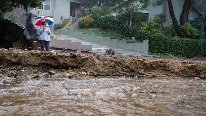 A resident keeps watch on Fredonia Drive in Studio City where a mudslide is blocking the road during the storm on Tuesday,