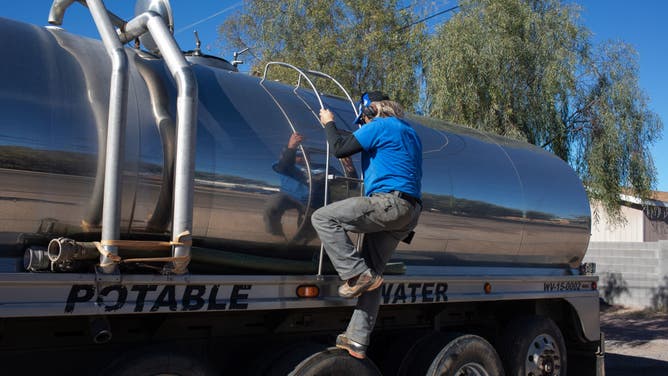 John Hornewer climbs down the ladder of his tanker as he fills it up to haul water from Apache Junction to Rio Verde Foothills, Arizona, U.S. on January 7, 2023.