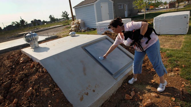 Woman shows off her newly built tornado shelter behind her Habitat for Humanity home on May 19, 2012 in Joplin, Missouri. One year prior, her home was destroyed by a tornado.