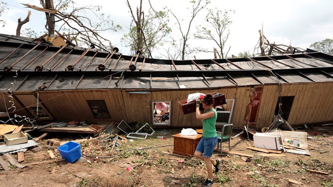 A volunteer helps clean up Jean McAdams' mobile home after it was overturned by a tornado May 20, 2013 near Shawnee, Oklahoma.