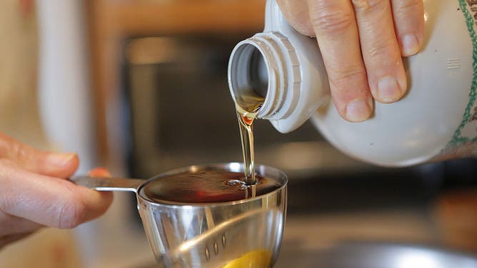 Maple syrup being poured into a measuring cup.
