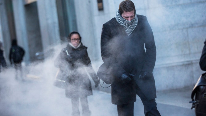 NEW YORK, NY - JANUARY 07: A man clenches his fists while walking past a steam vent on the morning of January 7, 2014 in New York, United States. A polar vortex has descended on much of North America, coming down from the Arctic, bringing record freezing temperatures across much of the country.
