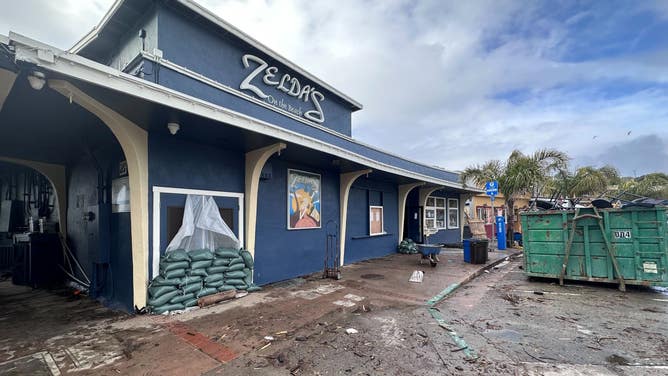 Sandbags and a dumpster filled with storm debris outside of Zelda's on the Beach.