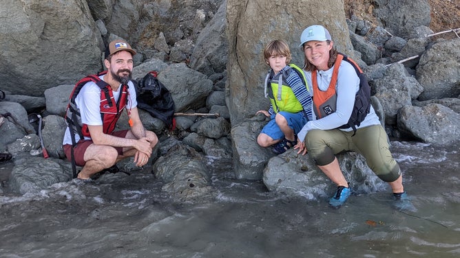 Cody Goddard with wife Laura MacLean and son Brennan on the day of discovery. The whale skull is in the partially submerged block of sediment just in front of, and below Cody’s left knee.