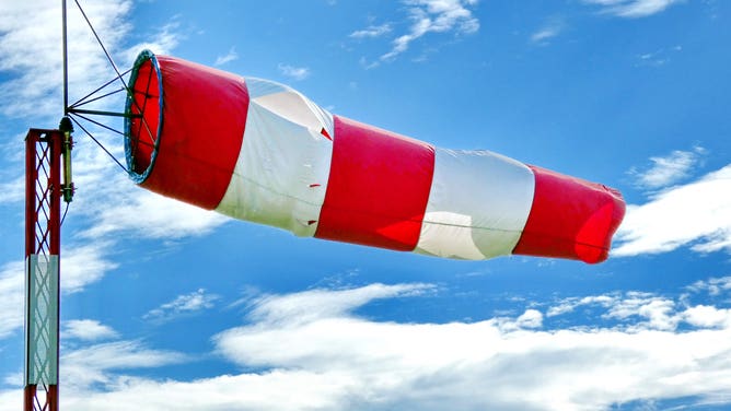 A red and white windsock blows in the wind.