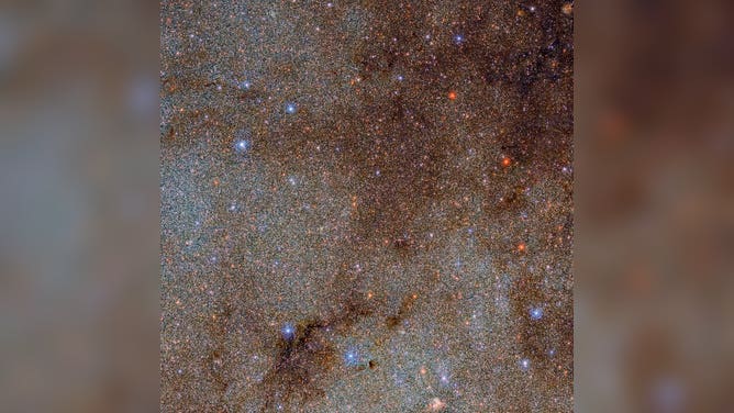 This image, which is brimming with stars and dark dust clouds, is a small extract — a mere pinprick — of the full Dark Energy Camera Plane Survey (DECaPS2) of the Milky Way.