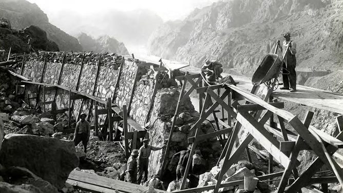 Masonry retaining wall on upper loop of highway under construction by Six Companies Inc. which will cross the crest of the dam.