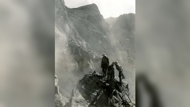 High scalers perched on a bench 1,000 feet above the river prepare anchorages from which workmen will be suspended by ropes in scaling the canyon walls for the penstock. August 22, 1932.