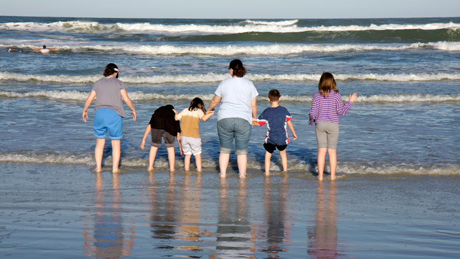 FILE - A family wading in the water at Flagler Avenue Beach in New Smyrna Beach, Florida.