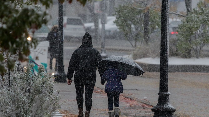 A mother walks with her daughter towards school during a snow shower morning at Boston, MA, 30 October 2020. 