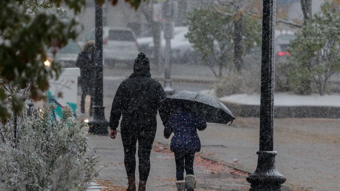 A mother walks with her daughter towards school during a snow shower morning at Boston, MA, 30 October 2020.