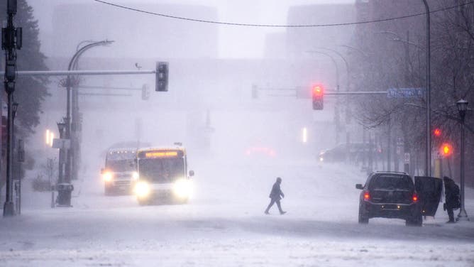 FILE - MINNEAPOLIS, MN - DECEMBER 23: A person walks through downtown as snow falls on December 23, 2020 in Minneapolis, Minnesota. Mid-forties temperatures this morning are giving way to high speed wind, low temperatures, and heavy snowfall, as blizzard warnings blanket the state.