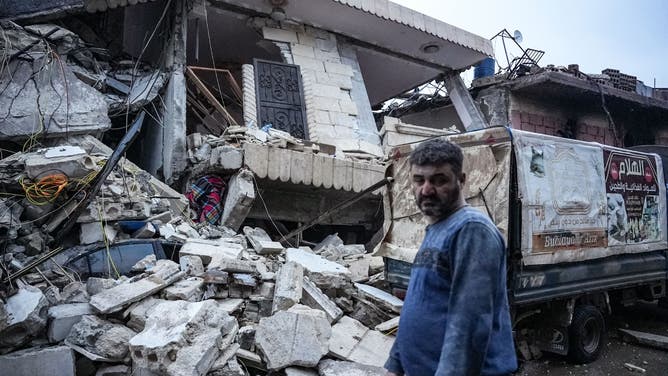 TOPSHOT - A resident stands in front of a collapsed building following an earthquake in the town of Jandaris, in the countryside of Syria's northwestern city of Afrin in the rebel-held part of Aleppo province, on February 6, 2023. - Hundreds have been reportedly killed in north Syria after a 7.8-magnitude earthquake that originated in Turkey and was felt across neighbouring countries. (Photo by Rami al SAYED / AFP) (Photo by RAMI AL SAYED/AFP via Getty Images)