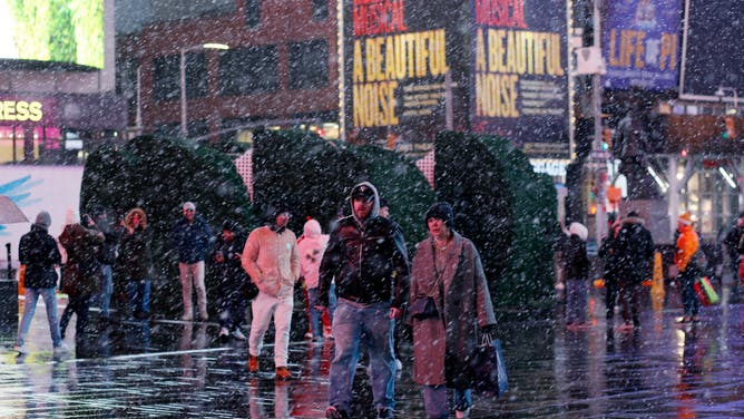 People visit Times Square during a snowfall on February 27, 2023 in New York City.
