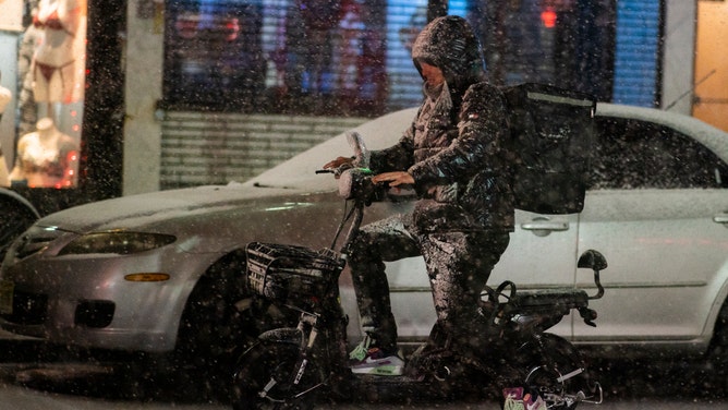 WEST NEW YORK, NEW JERSEY - FEBRUARY 27: A man tries to deliver some food as snow falls during a winter storm around Times Square on February 27, 2023 in Hoboken, New Jersey. The National Weather Service announced between 2 to 5 inches of snow to fall Monday night into Tuesday morning while other parts of the tri-state area, including northern New Jersey, could see more than a half-foot of accumulation associated with this storm.