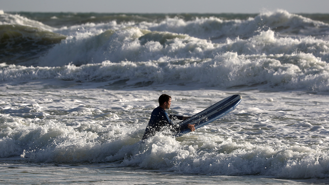 FILE - A surfer navigates waves and currents as the threat of Hurricane Dorian looms on September 1, 2019 in Ormond Beach, Florida.