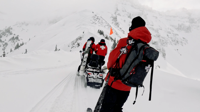 Ski patrol on skis and snowmobile.