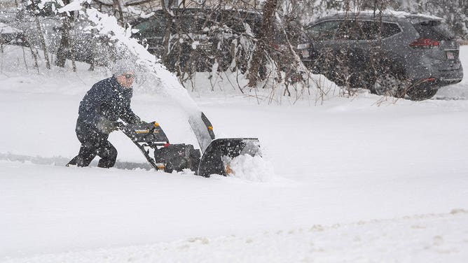A person tries to use a snowblower to clear snow from their driveway, over a foot deep, during a nor'easter in Rutland, Massachusetts, on March 14, 2023.