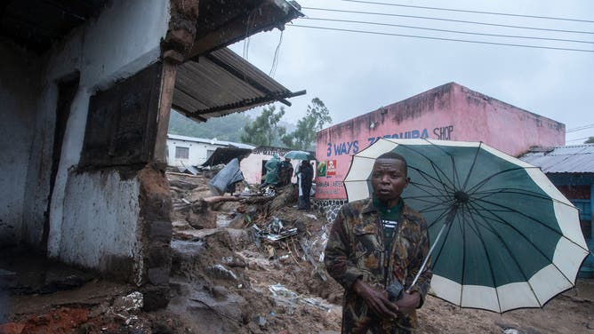 A man stands with an umbrella in Chimwankhunda, Malawi on March 14, 2023 following heavy rains caused by cyclone Freddy.