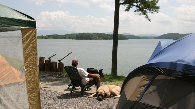 A man and his dog sit next to TVA Douglas Lake in Sevierville, Tennessee.