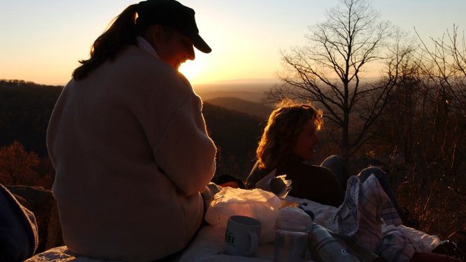 People enjoy a picnic and a sunset at Crescent Rock off of the Appalachian Trail in West Virginia.
