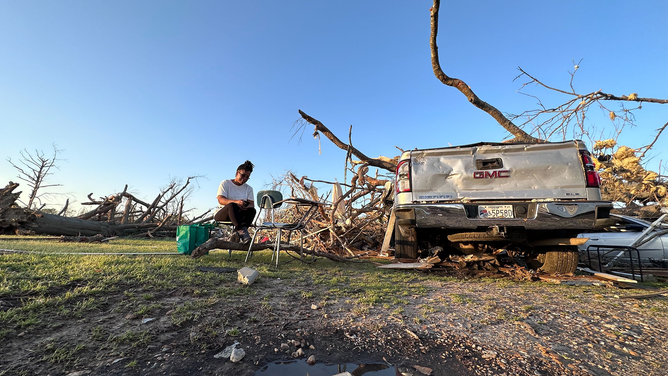 A woman is seen near a truck and what's left of her home after a tornado in Rolling Fork, Mississippi, on Friday, March 24, 2023.