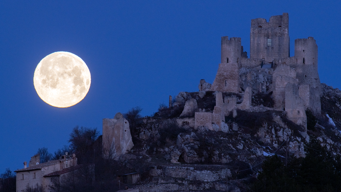 Full moon sets behind Rocca Calascio castle and village (LAquila), Italy, on March 7, 2023. March full moon is also known as the worm moon, because it coincides with the time of year when earthworms begin to emerge from the thawing soils.