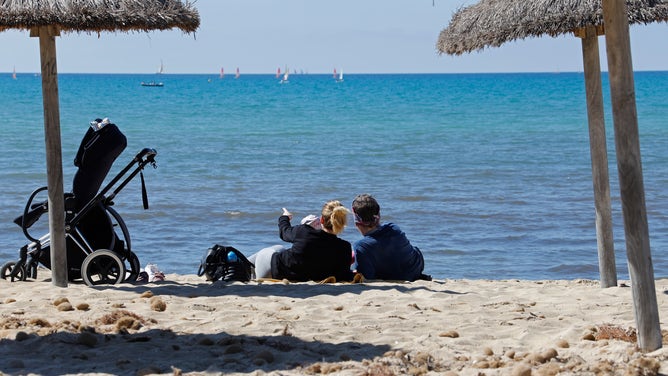 Holidaymakers lie in the low season on the beach of Arenal on the island of Mallorca. 