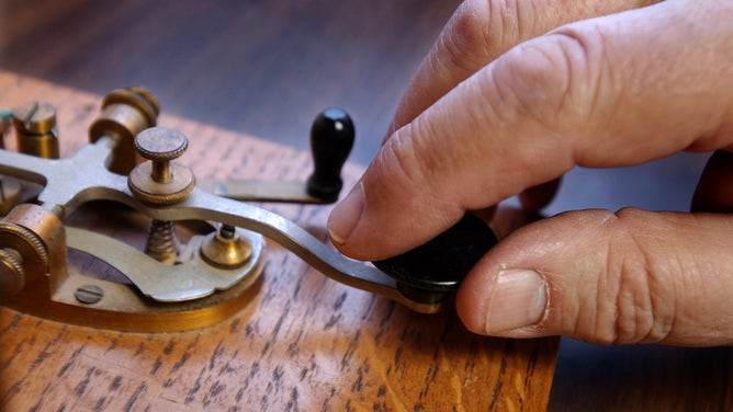 Telegrapher Bob Branchaud taps out a period in Morse Code on a hand key in his home office in Cottage Grove, Minnesota. April 20, 2004.