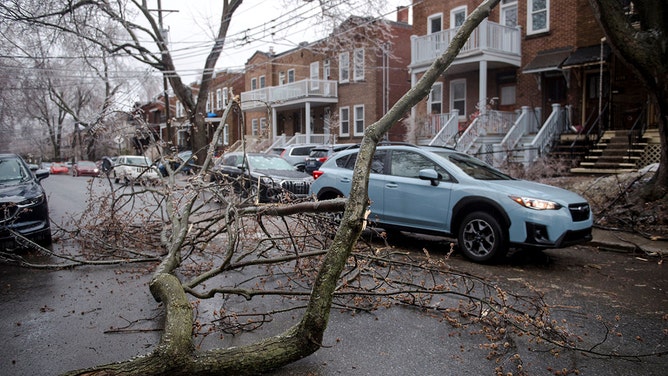 A car passes around after tree branches and power lines fell in Monkland Village after freezing rain hit parts of Quebec and Ontario in Montreal, Canada, on April 5, 2023.