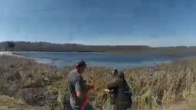 The rescuers pull the mother, her daughter and their dog onto shore.