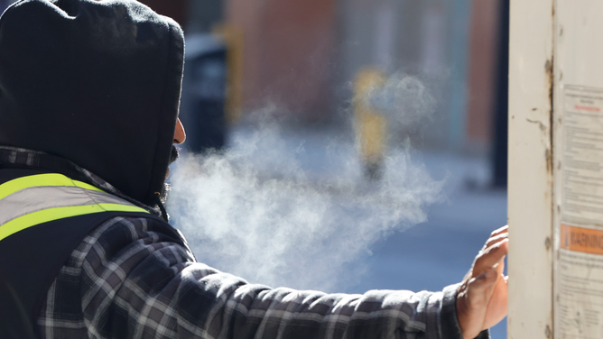 FILE - The breath of a worker on Yonge St. can be seen in the air on a bitterly cold day in Toronto.
