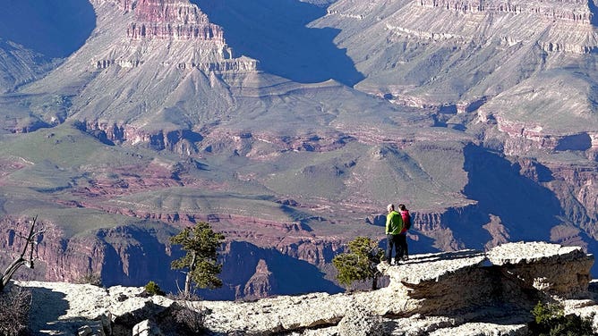 Tourists stand on a canyon rim at Grand Canyon National Park in Arizona during the spring of 2023.