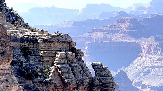 Tourists stand on an outcropping at Grand Canyon National Park in Arizona during the spring of 2023.