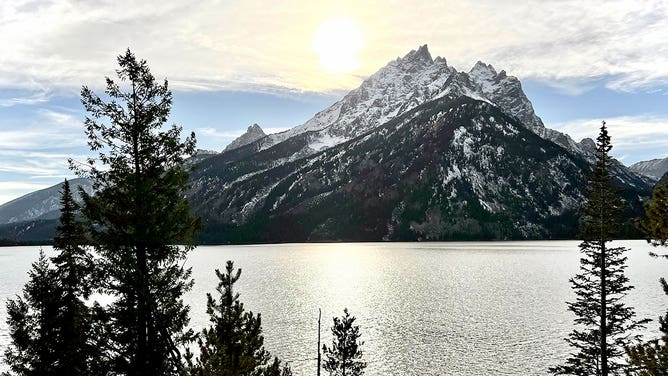 Mountains tower over a lake at Grand Teton National Park in Wyoming during the spring of 2023.