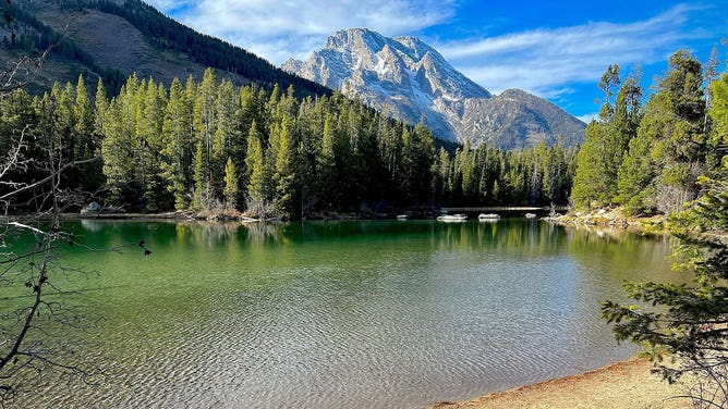 Mountains tower over a pond at Grand Teton National Park in Wyoming during the spring of 2023.