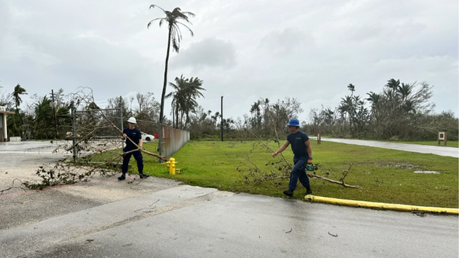 Members of Station Apra Harbor clear tree limbs as U.S. Coast Guard crews in Guam begin assessments and reconstitution efforts on May 25, 2023, after Typhoon Mawar devastated the island. Crews are working to resume operations and reopen the ports.