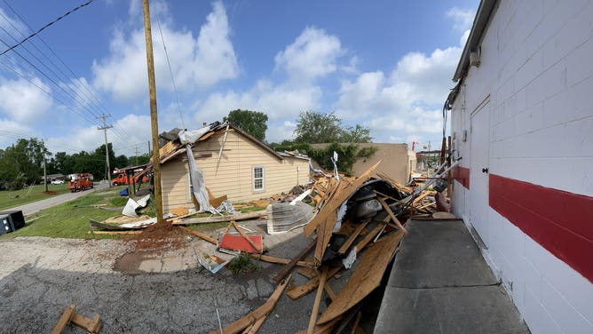 Wood planks and other rubble cover a car.