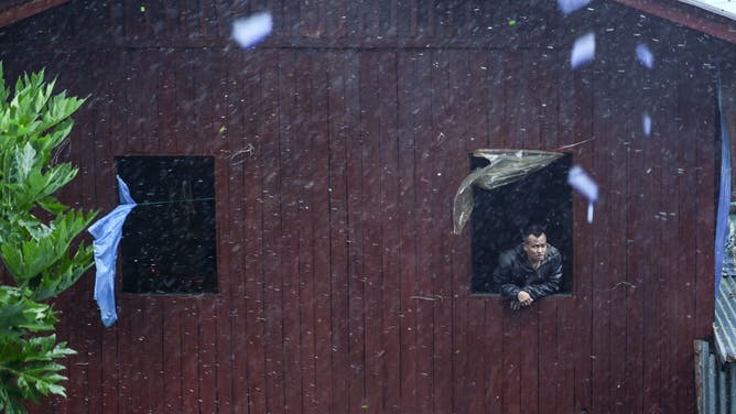 A local resident looks from a window in Kyauktaw in Myanmar's Rakhine state on May 14, 2023, as Cyclone Mocha's crashes ashore. Cyclone Mocha crashed ashore in Myanmar and southeastern Bangladesh on May 14, 2023, uprooting trees, scattering flimsy homes in Rohingya displacement camps and bringing a storm surge into low-lying areas.