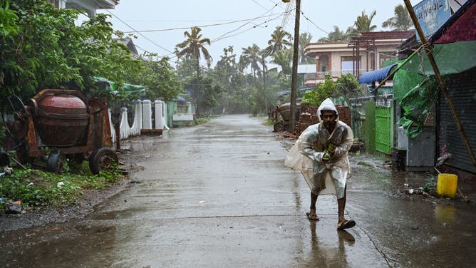 A local resident walks in the rains in Kyauktaw in Myanmar's Rakhine state on May 14, 2023, as Cyclone Mocha's crashes ashore. Cyclone Mocha crashed ashore in Myanmar and southeastern Bangladesh on May 14, 2023, uprooting trees, scattering flimsy homes in Rohingya displacement camps and bringing a storm surge into low-lying areas.