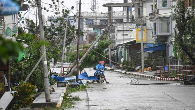 Local residents ride their motorbike amid a damaged street after Cyclone Mocha's crashed ashore, in Kyauktaw in Myanmar's Rakhine state on May 14, 2023. Cyclone Mocha crashed ashore in Myanmar and southeastern Bangladesh on May 14, 2023, uprooting trees, scattering flimsy homes in Rohingya displacement camps and bringing a storm surge into low-lying areas.
