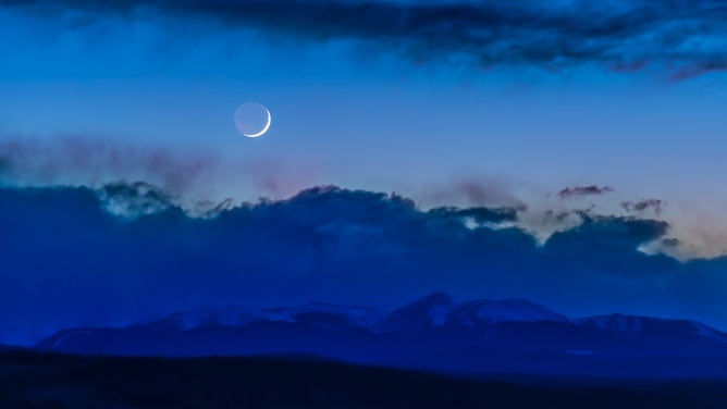 FILE - The waxing 2-day-old crescent Moon setting over the front range of the Rocky Mountains in southern Alberta, as seen from the Rothney Astrophysical Observatory, April 6, 2019. Earthshine is visible on the night side of the Moon.