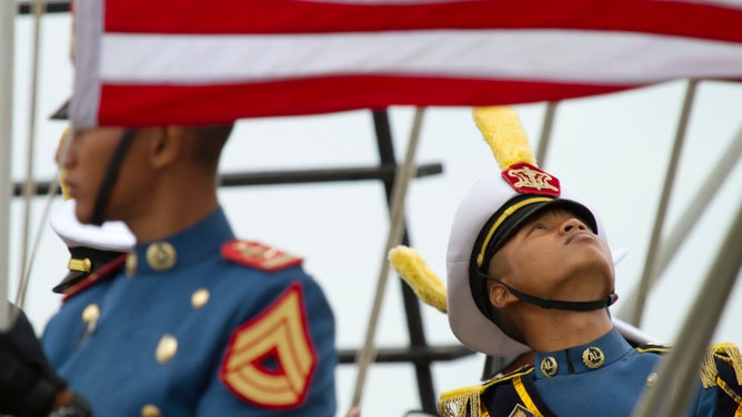 A sailor looks up as an American flag whips in the breeze. June 12, 2012.