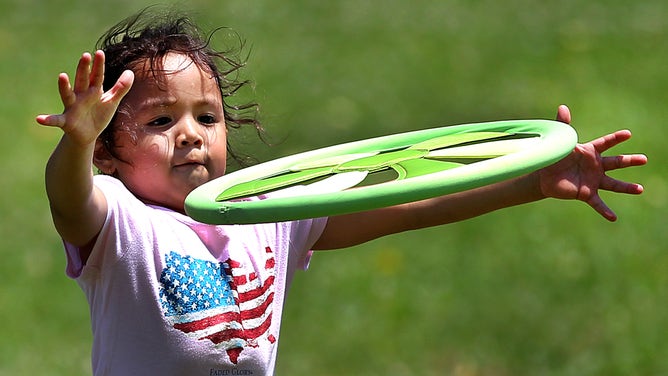 A little girl tries to catch a disk thrown to her at Carson Beach in Boston. July 6, 2012.