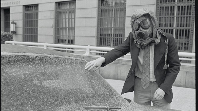 Man with Gas Mask Examining Car