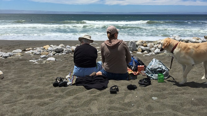People sit along Rockaway Beach in Pacifica, California, in July 2015.