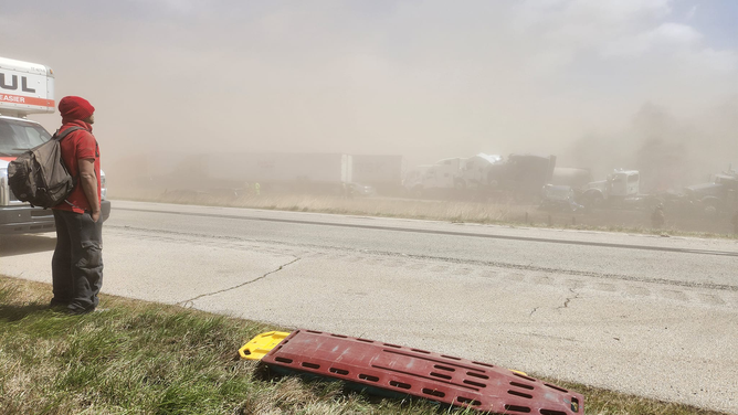 A person is seen standing next to a massive pileup after a dangerous dust storm on I-55 in Illinois on May 1, 2023.